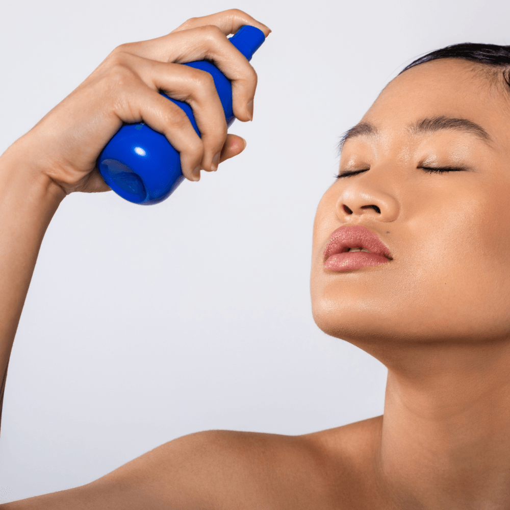 Model spraying REMAKE TeaTox Glow Serum Mist onto face, delivering green tea antioxidants and hyaluronic acid hydration