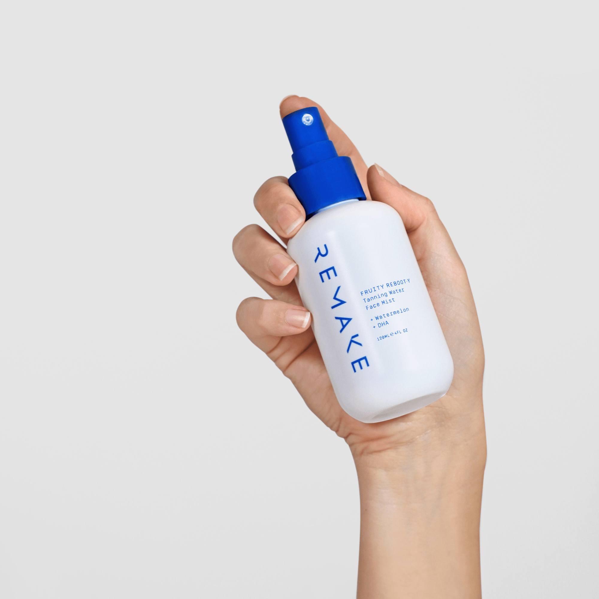 Hand holding Fruity Re-Booty Face Tanning Mist, natural antioxidant self tan spray for glowing hydrated skin