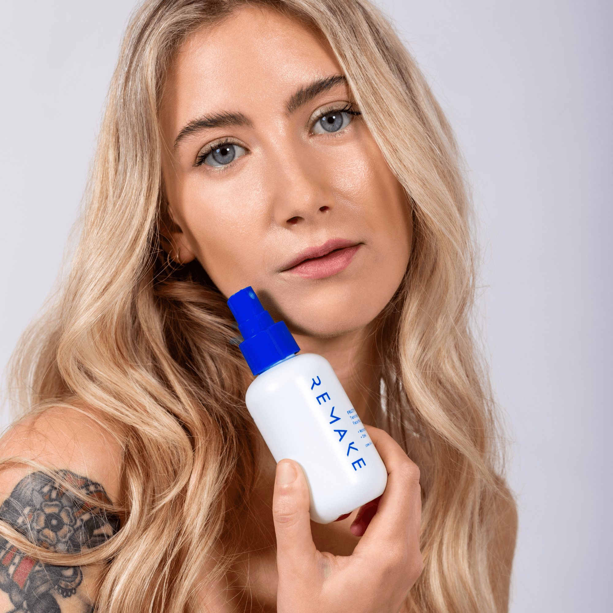 Model holding Fruity Re-Booty Face Tanning Mist close to face, antioxidant fruit blend self tan spray for tanned skin