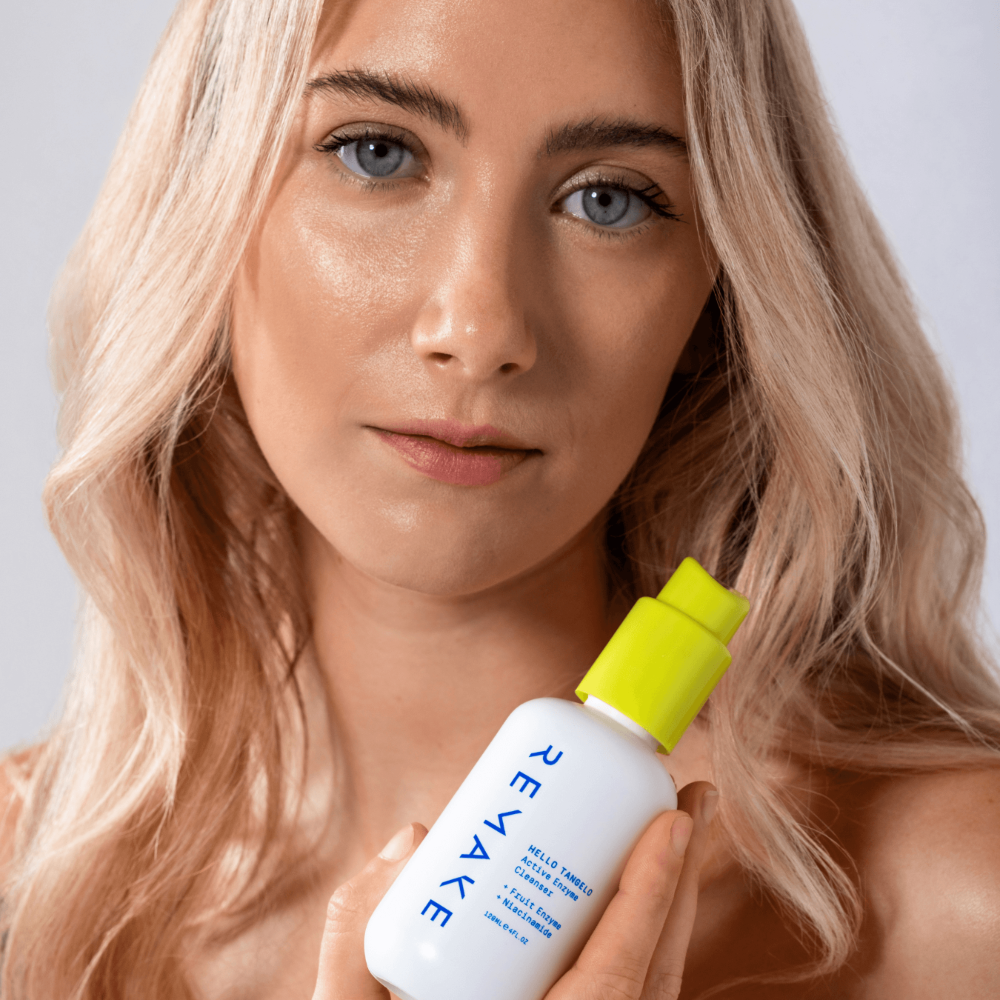 Model holding Hello Tangelo Active Enzyme Cleanser near face, fruit enzyme Vitamin C wash with niacinamide for radiant skin